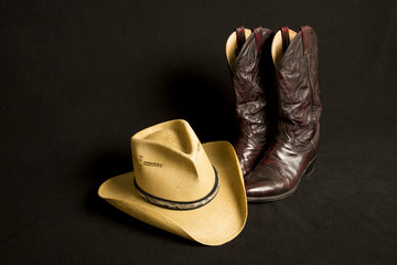 Cowboy boots and cowboy hat on black background