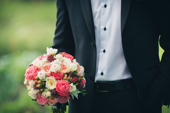 groom holding bridal bouquet on a green background