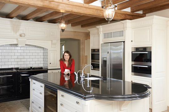 Mature Woman Standing In New Luxury Fitted Kitchen