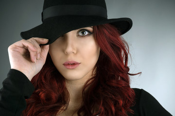 Young woman covering her eye with a fedora hat