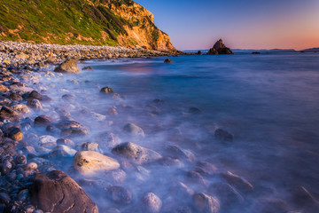 Long exposure of waves crashing on rocks at sunset, taken at Pel