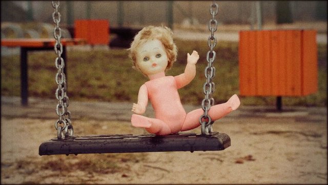 Abandoned doll on a swing in retro style