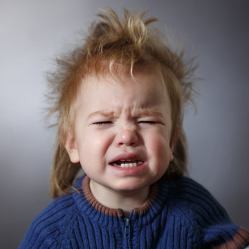 portrait of a weeping baby on a dark background