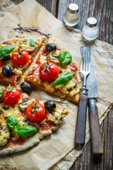 Fresh pizza on paper and old wooden table