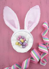 Easter bunny ears on pink wood background.