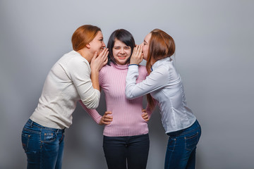 two girlfriends European appearance whisper in the ear of