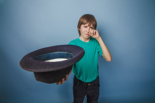 boy teenager European appearance in green t-shirt holding a hat