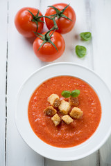 Tomato soup Gazpacho over white wooden background, above view