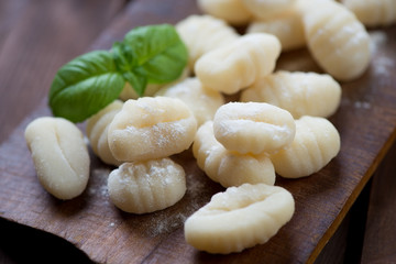Fototapeta na wymiar Close-up of raw gnocchi with flour and green basil, studio shot