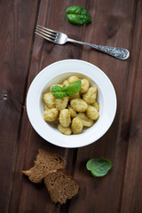 Italian gnocchi with basil pesto over dark wooden background