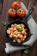 Gnocchi with tomato sauce and basil in a frying pan, above view