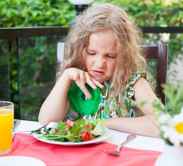 Child with disgust looking at salad