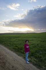 Ni&ntilde;a disfrutando de la puesta de sol en el campo