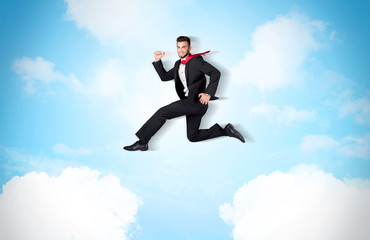 Business person jumping over clouds in the sky