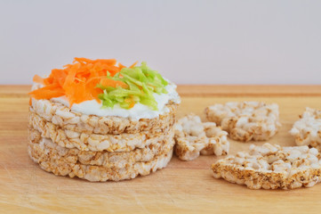 Fototapeta na wymiar Rice cakes with white low fat cheese spread, carrot and cucumber