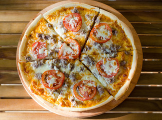 Fresh hot pizza with tomatoes on wooden background