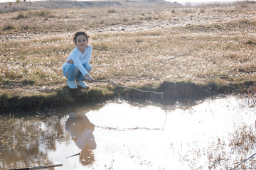 Niña pescando ranas en la charca