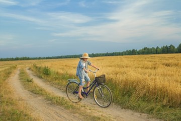 Fototapeta na wymiar Teenager boy rides a bicycle on country road