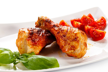Grilled chicken legs and vegetables on white background