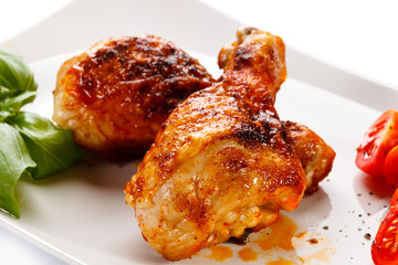 Grilled chicken legs and vegetables on white background