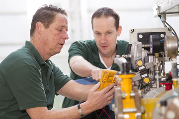 Two male technicians repairing agriculture machinery