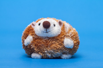 Fototapeta premium Cute small stuffed hedgehog toy over a blue background.