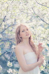 Sunny portrait of a beautiful young woman in a flowering spring