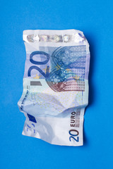 Twenty euros bill wrinkled over a blue background.