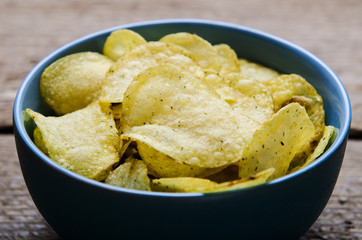 chips with herbs in blue bowl on a wooden table