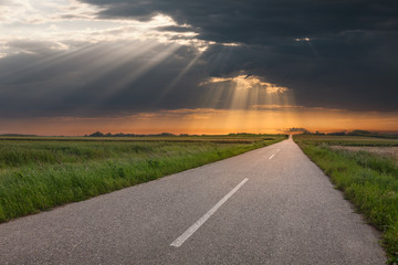 Driving on an empty country road at sunset