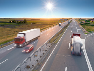 Trucks and car on the freeway at sunrise