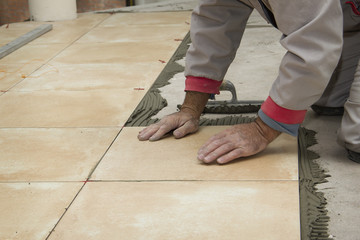 Home improvement, renovation - handyman laying tile with level