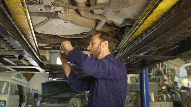 Mechanic taking photographs of car damage for insurance purposes
