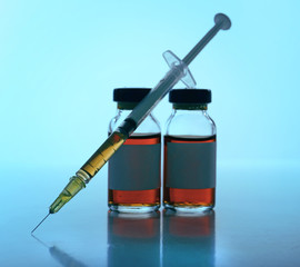 Medical ampule with syringe on blue background