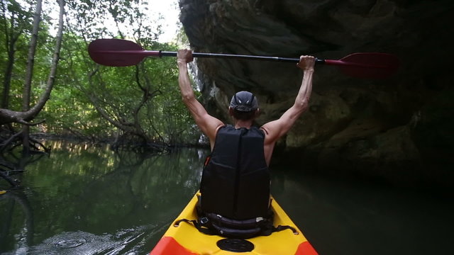 Man Drifts In Kayak And Lifts Paddle Over Head	