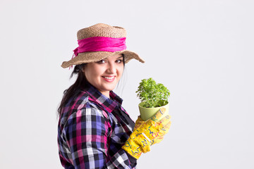 Woman Gardener in Leghorn Holds a Green Plant in Flowerpot