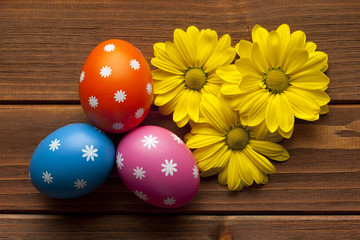 Obraz na płótnie Canvas Colored Easter eggs and flowers on wooden background