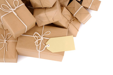 Untidy pile or heap of several lots brown paper wrapped parcel package or gift boxes one with blank label or gift tag isolated on white background photo