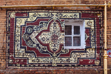 Painted rug on a brick wall