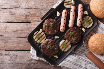 Burgerі and sausages on a grill pan horizontal top view