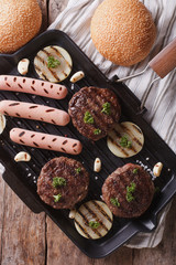 burgers and hot dogs on the grill pan closeup. vertical top view