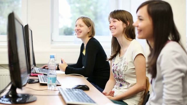 College students sitting in a classroom, using comput