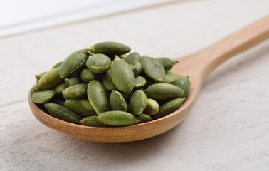 pumpkin seeds in the spoon on white wooden