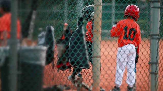 Kids playing around as they wait to bat at baseball game