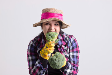 Garden Woman in Leghorn Holds is Biting a Broccoli