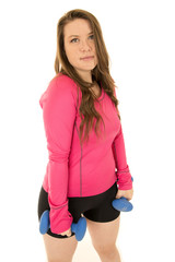 Young brunette woman standing holding blue barbells no smile