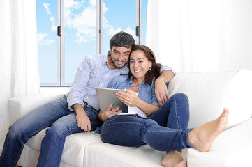 Obraz premium happy couple on home couch enjoying using digital tablet