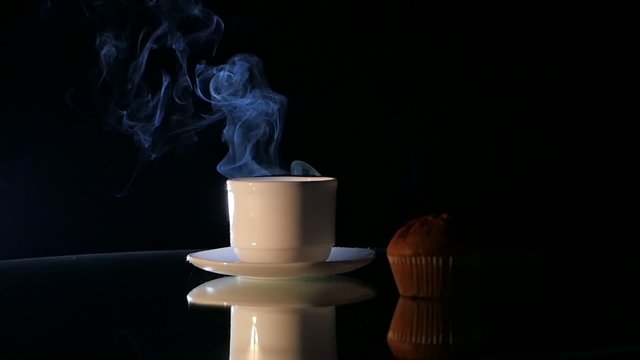 Hot coffee in white cup with cake on black background