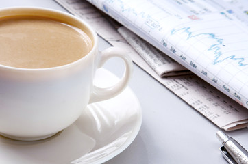 Cup of coffee near the laptop and newspapers