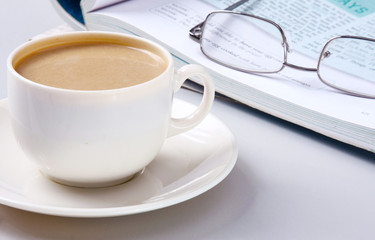 Cup of coffee near the laptop and newspapers